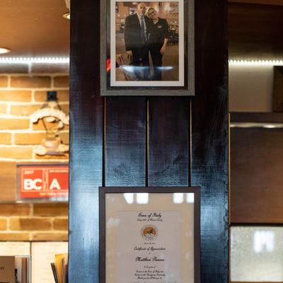 Framed items including a portrait and a certificate on a wooden-paneled wall.
