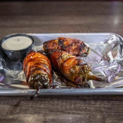 Fried bacon wrapped jalapenos stuffed with cream cheese, side view.