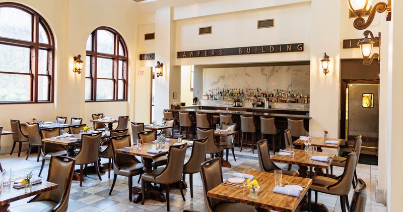 Bright dining room - leather chairs, set tables, a stocked bar.