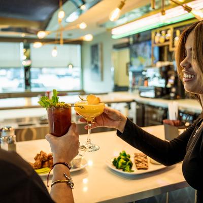 Two people toasting with colorful cocktails.