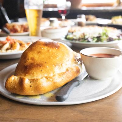 Calzone served with marinara sauce and other dishes in the background.