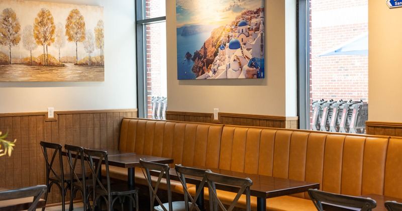 Interior - tables and chairs, artwork of trees and a Santorini landscape on the walls