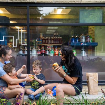 People sitting and eating outside with their children.