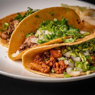 Tacos al pastor on a white plate, close up.