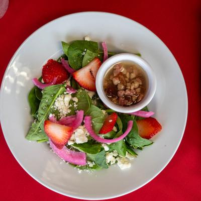 Spinach salad, with red onions, strawberries, feta cheese, prosciutto, and vinaigrette.