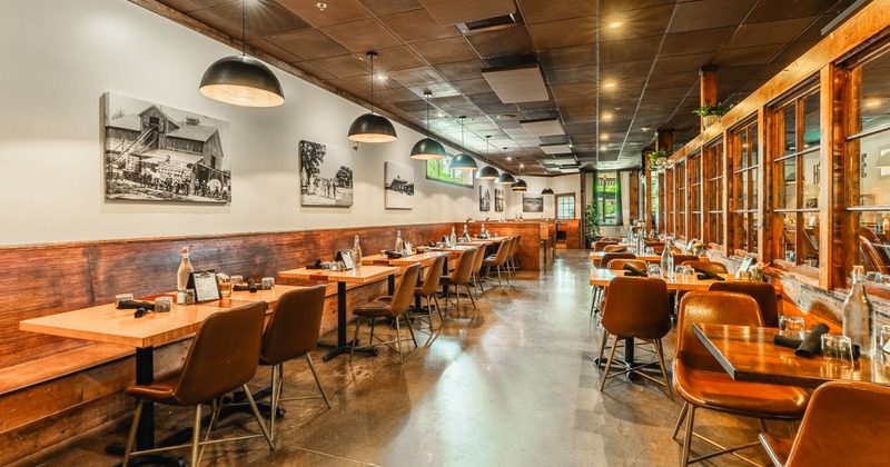 Interior seating area with wooden tables, leather chairs and pendant lights