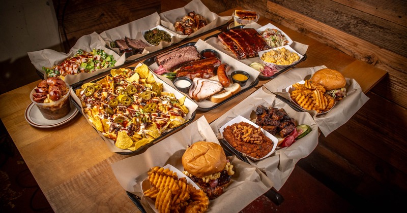 Assorted dishes on a table including ribs, brisket, nachos, and burgers
