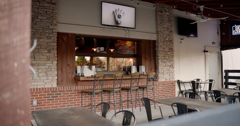 Outdoor seating area with tables, chairs, and a wooden counter with stools
