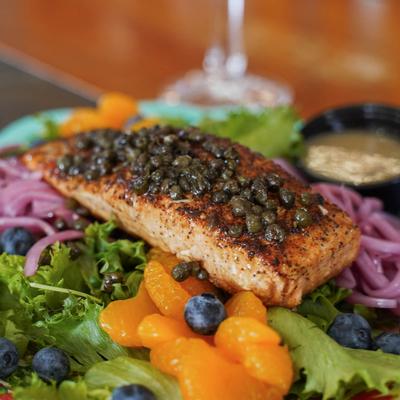 Seared salmon topped with capers, served over mixed greens, blueberries, and tangerines.
