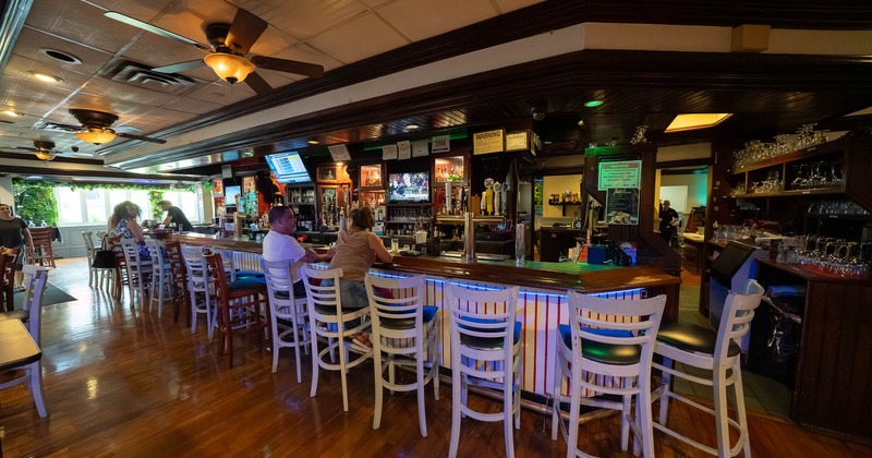 Interior of a bar with a wooden counter and white bar stools