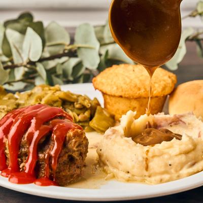Meatloaf topped with tomato glaze alongside gravy-topped mashed potatoes.