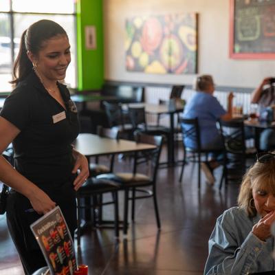 A friendly waitperson interacts with guests at a table in dining area.