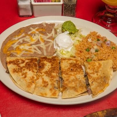 Quesadilla dinner plate featuring refried beans, Mexican rice, guacamole, and sour cream.