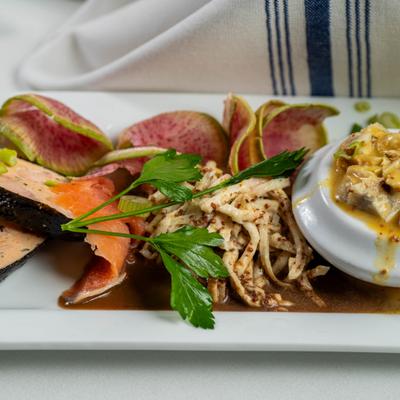 A gourmet seafood platter with salmon, radish slices, and creamy tartar sauce.