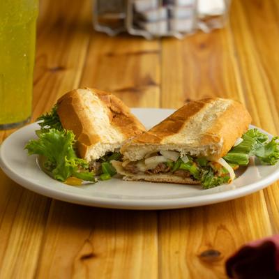 A plate with a Steak Hoagie is on a dining table.