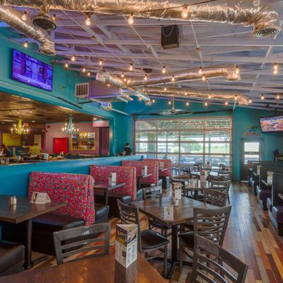 Interior with booths, tables, chairs, and string lights