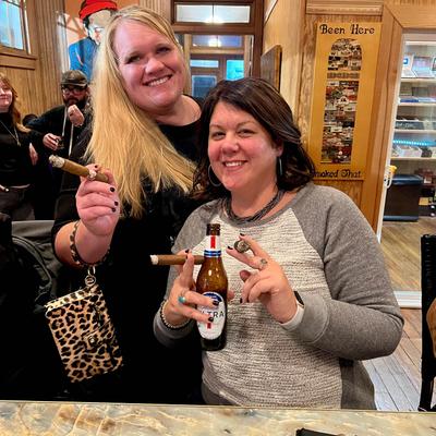 Two people enjoying drinks and cigars.