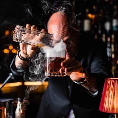 A bartender preparing a smoky cocktail.