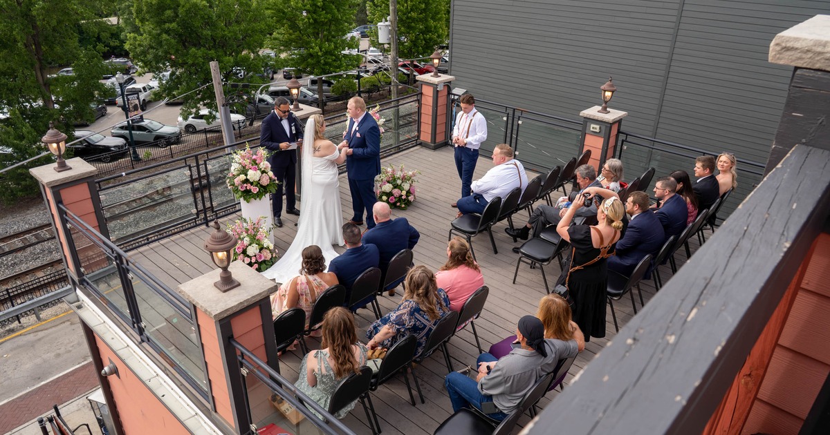 Rooftop ceremony featuring a couple standing and guests seated on the deck