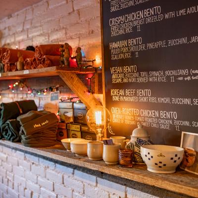 Wooden shelves displaying various items and a chalkboard menu on a white brick wall.