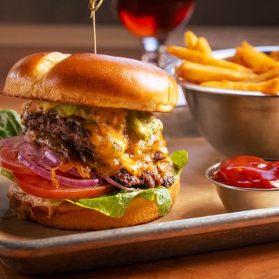 Cheeseburger with melted cheddar, avocado smash, red onion , fries, and ketchup.