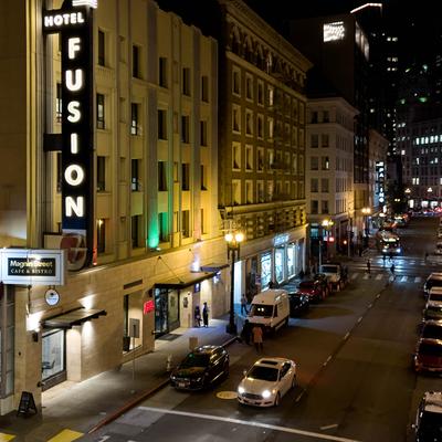 Street view with illuminated hotel sign at night.