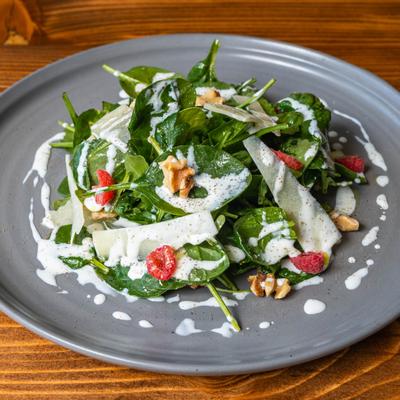 Arugula salad with shaved cheese, nuts, raspberries, and dressing.