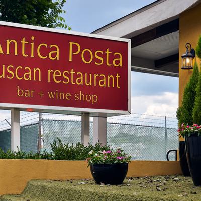 Restaurant sign beside landscaped entrance.