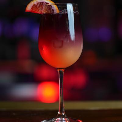 Cocktail in a wine glass garnished with slice of grapefruit.