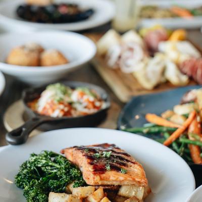 Glazed salmon served with potatoes, broccolini, and surrounding dishes.