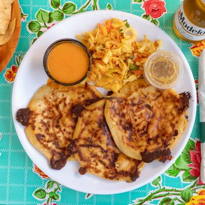 Pupusas served with spicy fermented cabbage slaw and sauces.