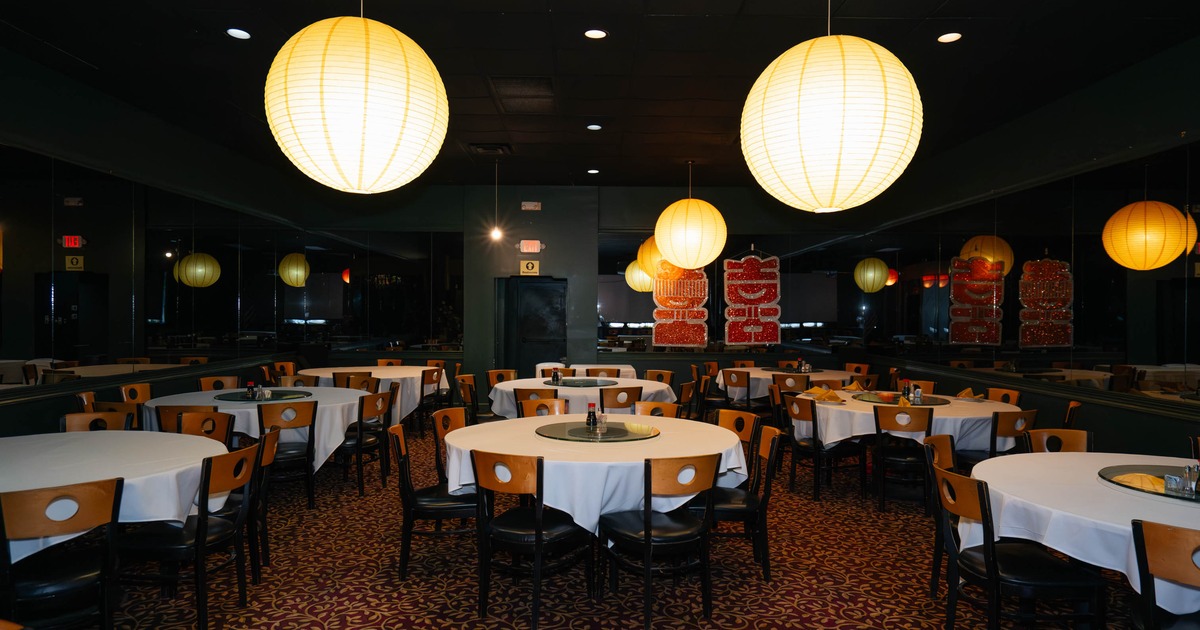 Interior, round tables, white tablecloths, and large yellow paper lanterns hanging from the ceiling