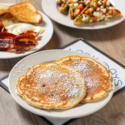 Blueberry pancakes, classic breakfast plate, and a plate with guacamole toast.