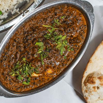 Indian curry garnished with cilantro, served with rice and naan bread.