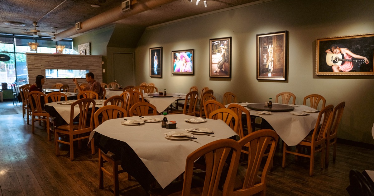 Cozy interior with round tables,  wooden chairs and framed artwork on the walls.