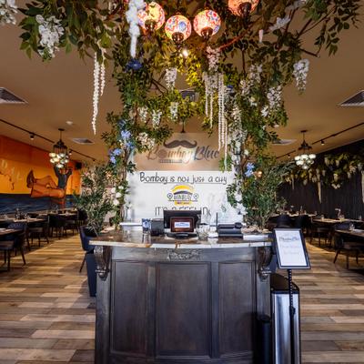 A restaurant interior with hanging greenery and decorated ceiling lights.