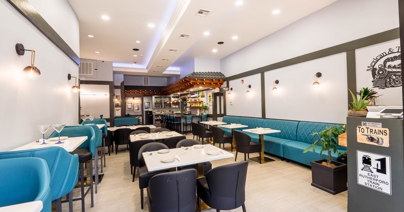 Modern restaurant interior with blue and black seating, bright lighting, and a bar area