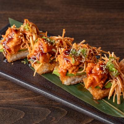Crispy rice topped with fried shrimp, garnishes, and sauce.