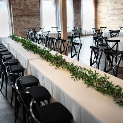 Reception space, long and round wedding tables with black crossback chairs.