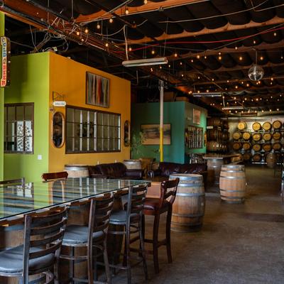 Vibrant interior with colorful walls, tables, wooden barrels, and string lights.