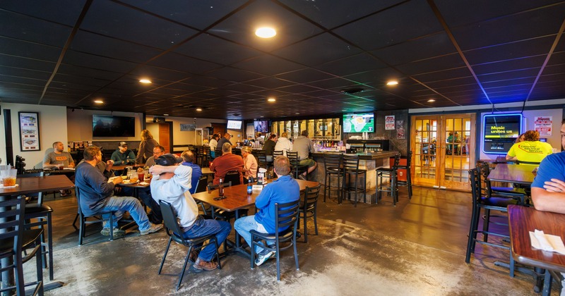 Interior, seating space with tables and chairs, bar and TV screen