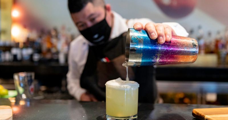 Interior, bartender pouring a cocktail from shaker, closeup