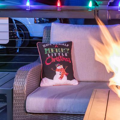 Festive outdoor scene with a cozy wicker chair and a snowman pillow.