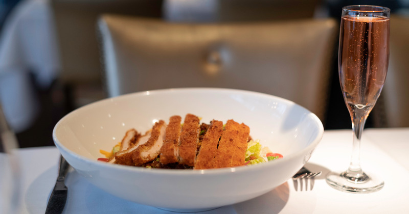 Breaded fried chicken served over vegetables, and a glass of champagne