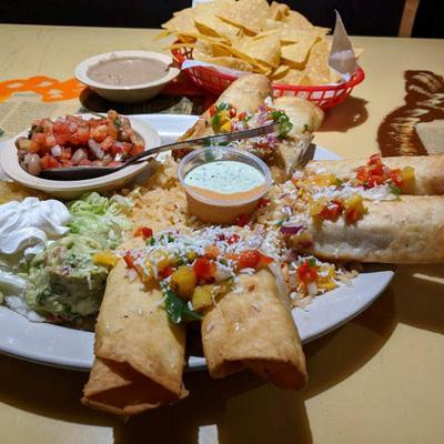 Plate of flutas with varios sides served with a basket of naachos.