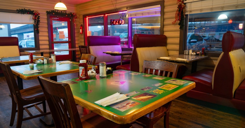 Interior, dining area, wooden top tables for four, seating booths in the back, entrance