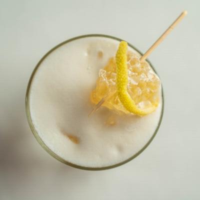 Cocktail with foam and lemon twist garnish, overhead view.