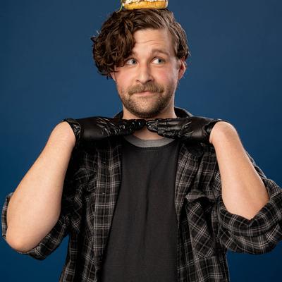 A person posing with a burger on their head.