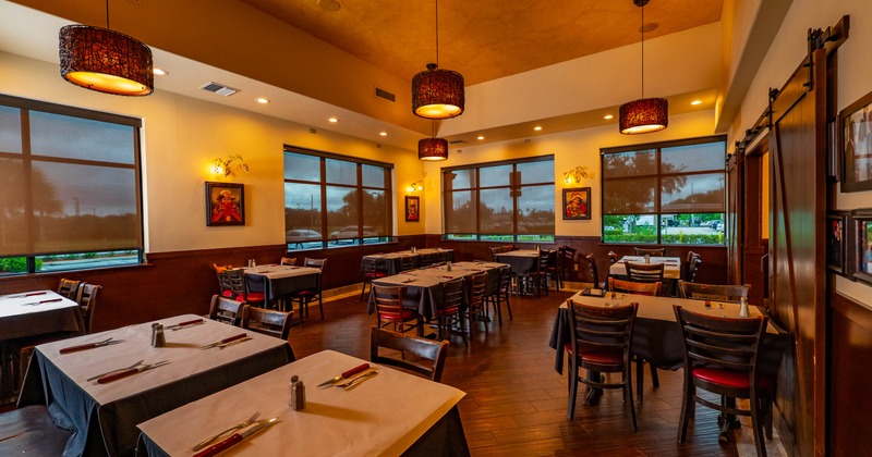 Interior of a restaurant with decorated tables, pendant lighting, and large windows