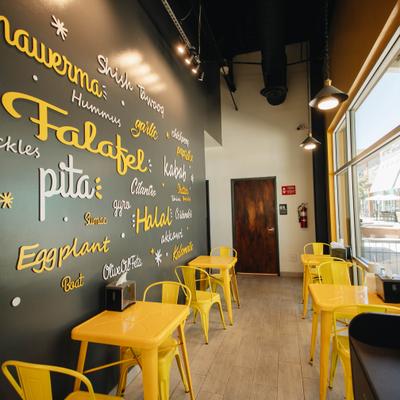 Interior featuring bright yellow chairs and tables against a dark accent wall.